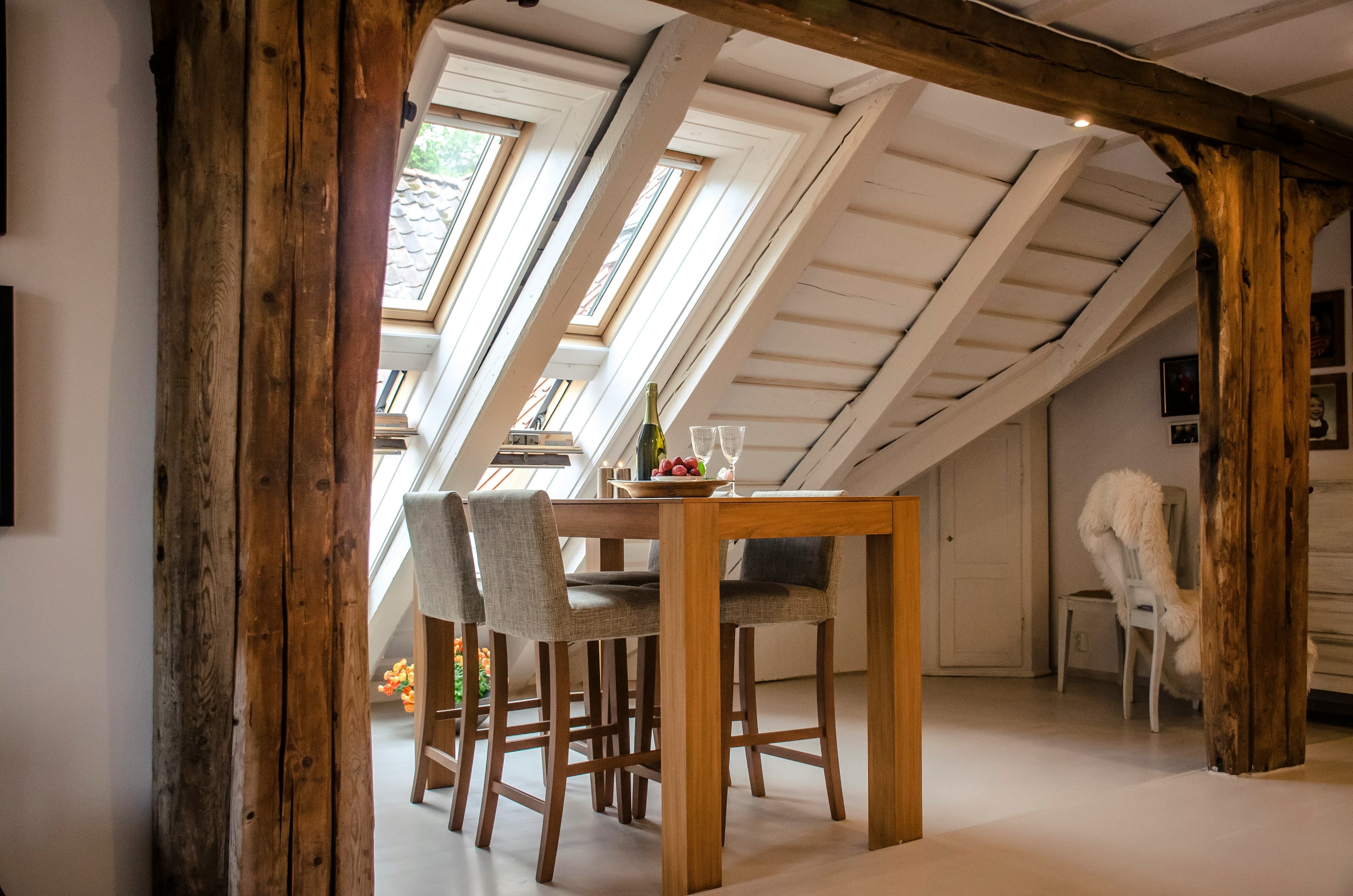 Loft dining space under exposed beams and rooflights